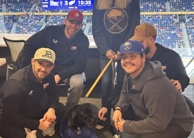 A group of people posing with a dog with a stadium backdrop