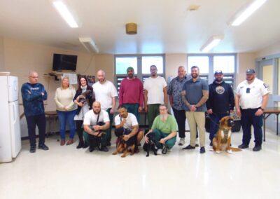 a large group of people posing with dogs in a bright lighted facility